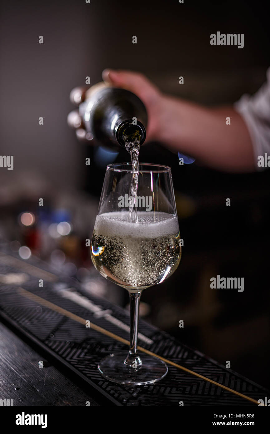 Barmann versa dello champagne nella Wineglass sul bancone del bar Foto Stock