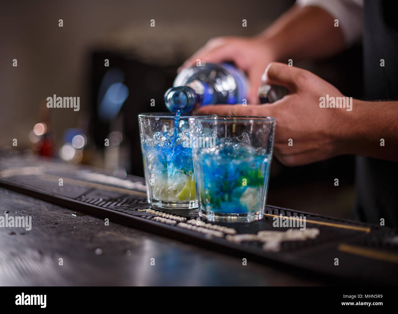 Barman drink di versare in un bicchiere da cocktail riempito con cubetti di ghiaccio Foto Stock