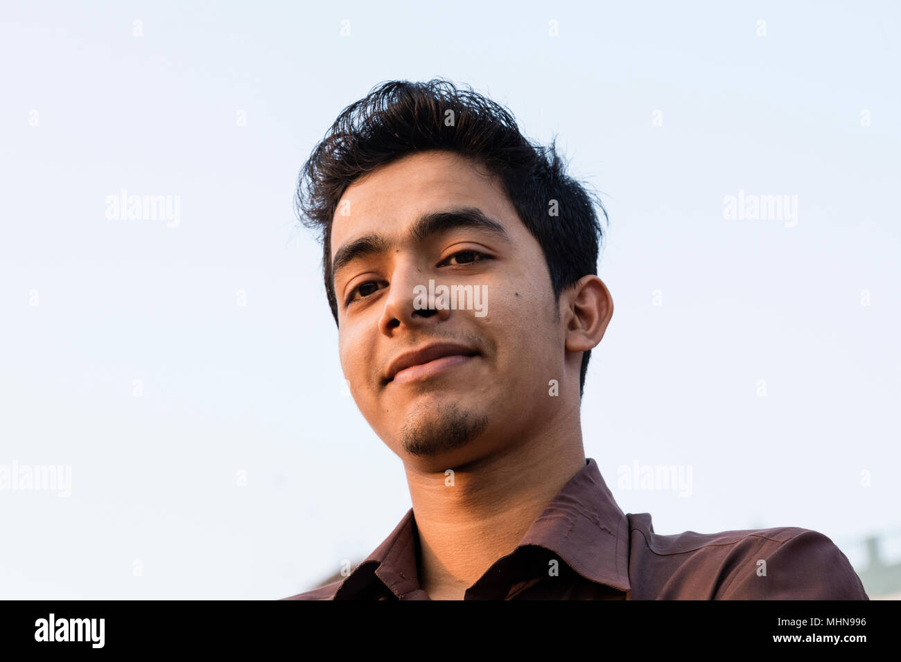 Dacca in Bangladesh, 24 Febbraio 2017: Ritratto di una giovane sorridente uomo del Bangladesh con una maglietta marrone nella luce della sera presa dal basso Foto Stock