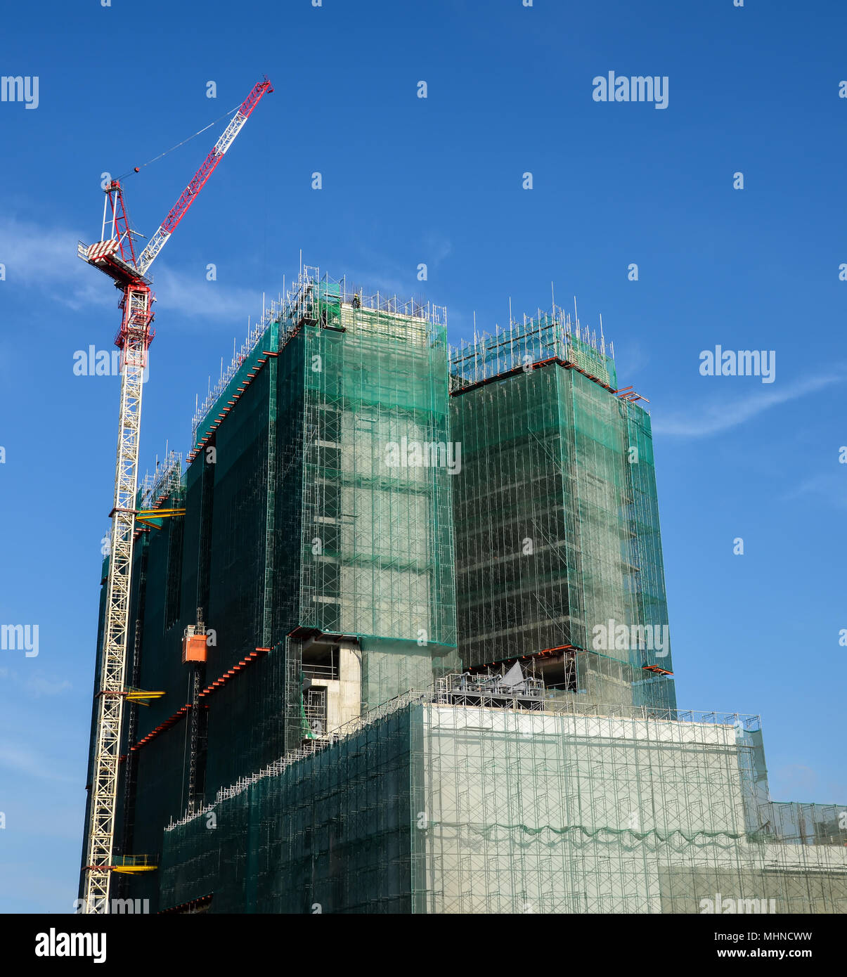 Utilizzando un ponteggio che copre in alto edificio costruzione Foto Stock