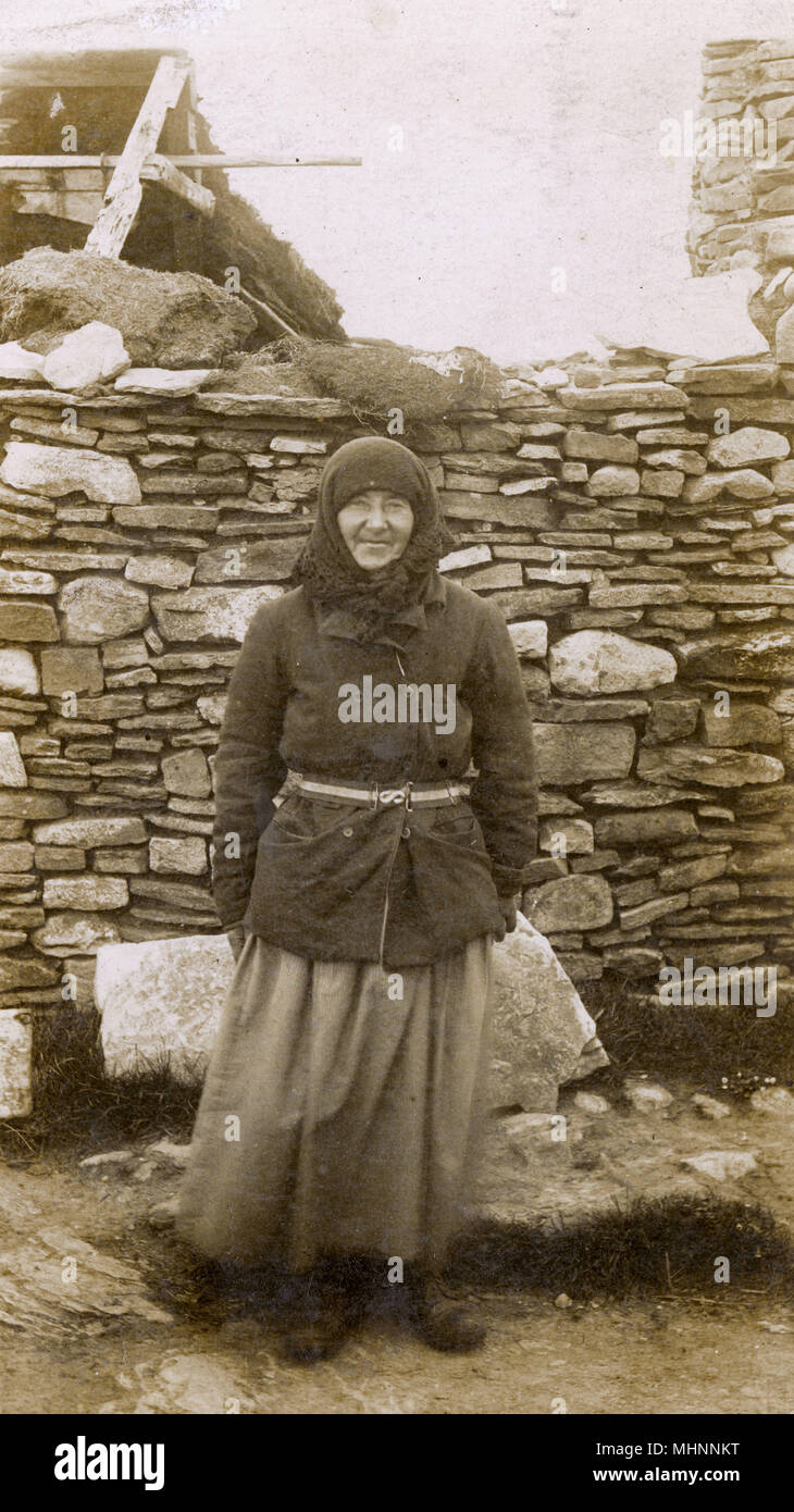 Una donna locale delle isole di Orkney al di fuori di casa sua. Orkney è stato il sito di un Royal Navy base a Scapa Flow, dove il marinaio che ha inviato questa carta era di stanza (l'HMS Royal Arthur) nel giugno 1916, quando ha inviato questa scheda. Data: circa 1922 Foto Stock
