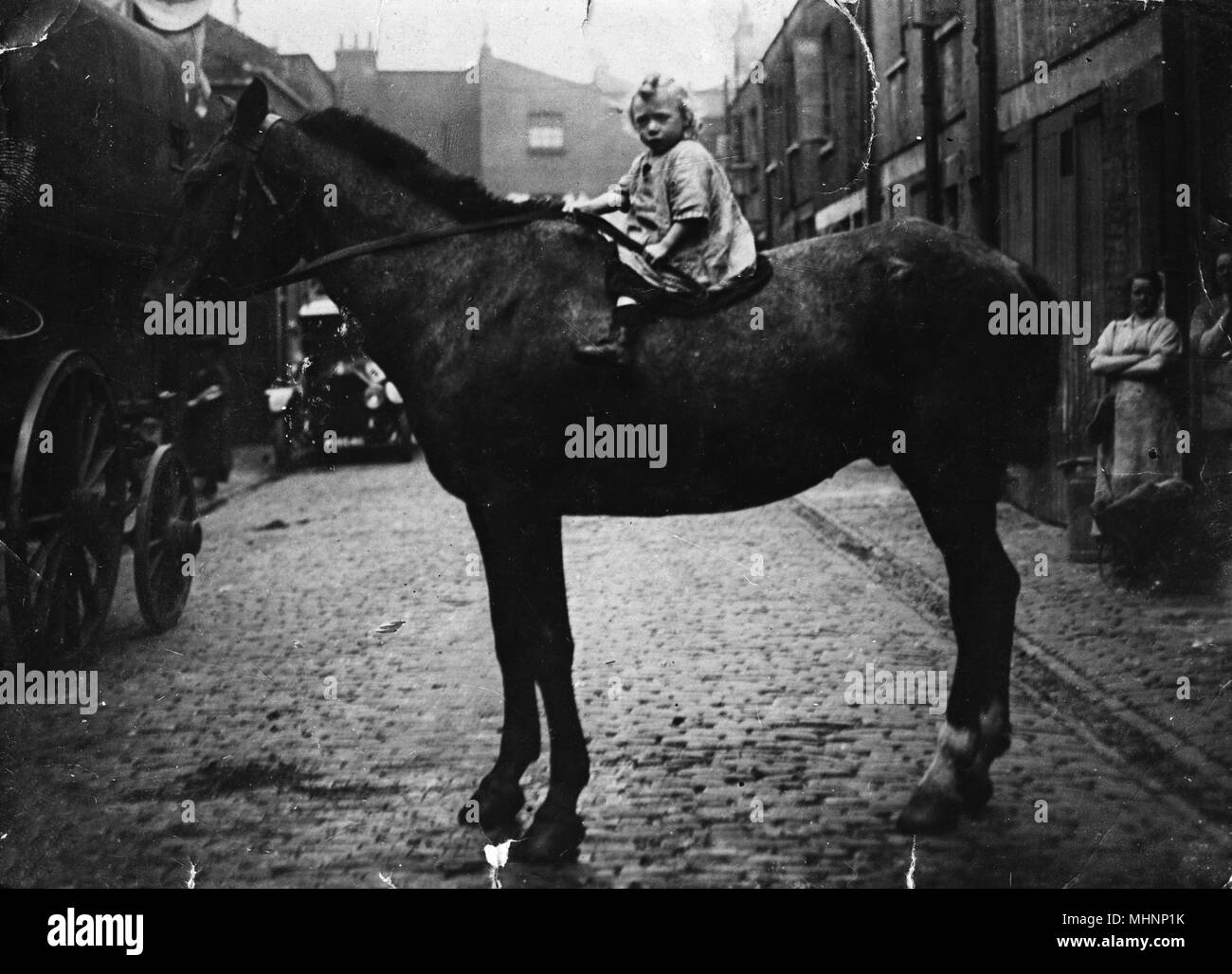 Famiglia con cavalli, Huntsworth Mews, Marylebone, London -- un bambino seduto su un cavallo. Data: circa 1910 Foto Stock