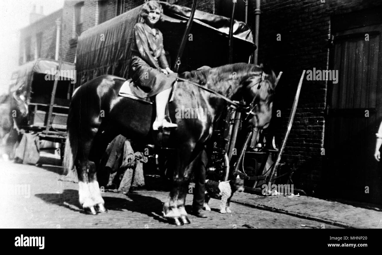 Famiglia con cavalli, Huntsworth Mews, Marylebone, London -- una donna seduta su un cavallo, con un piccolo cane in piedi accanto a. Data: circa 1910 Foto Stock