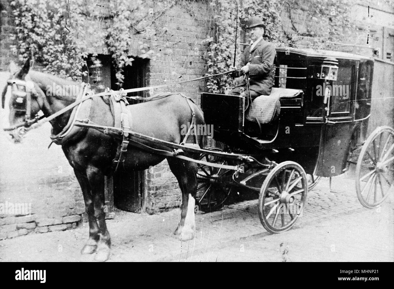 Famiglia con cavalli, Huntsworth Mews, Marylebone, London -- uomo in smart vestiti e un Bowler cappello con una carrozza trainata da cavalli. Data: circa 1910 Foto Stock