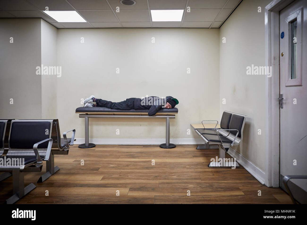 Glasgow in Scozia, Glasgow Central uomo dorme sul banco in sala d'attesa Foto Stock