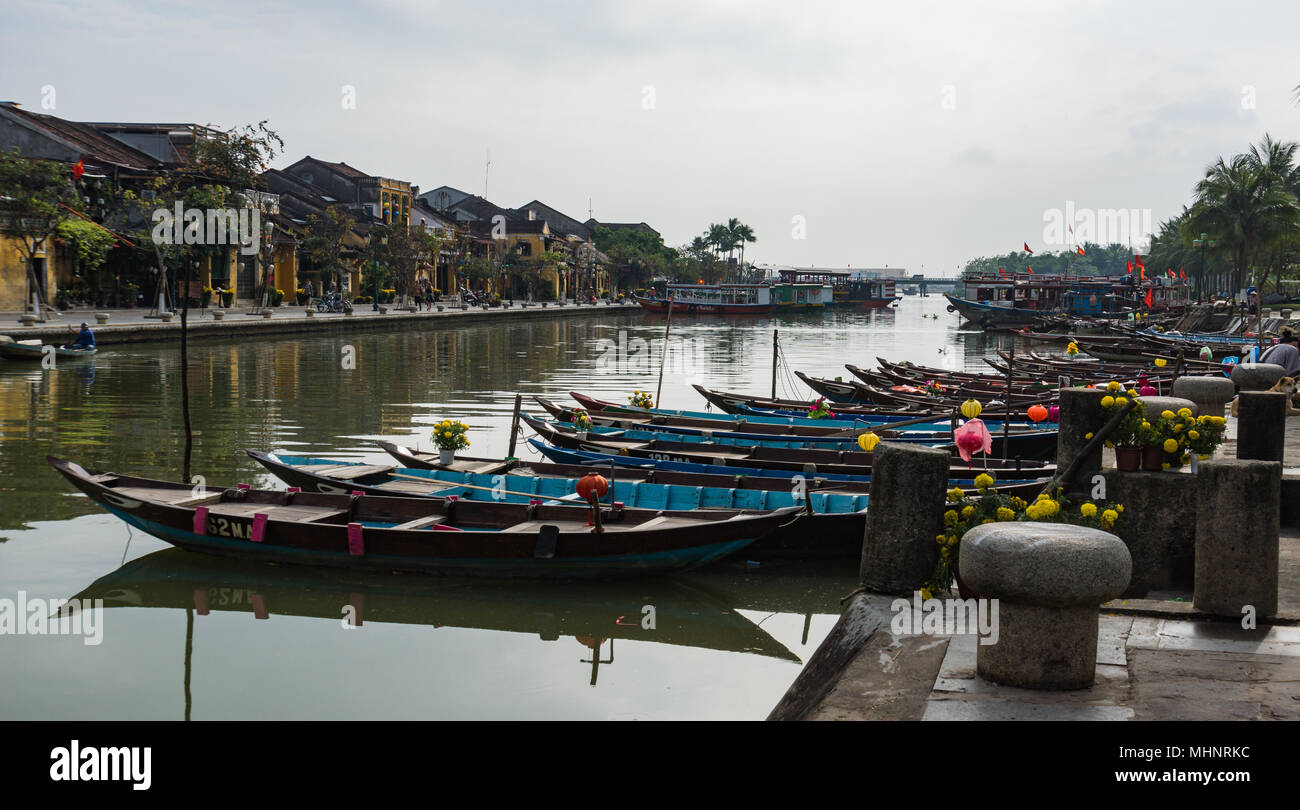 Barche con fiori di colore giallo e lanterne legato lungo il fiume nella vecchia città di Hoi An, Vietnam Foto Stock