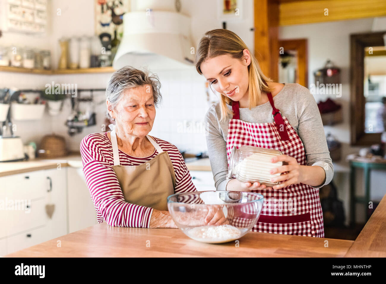 Una nonna con un adulto nipote a casa, cottura. Foto Stock