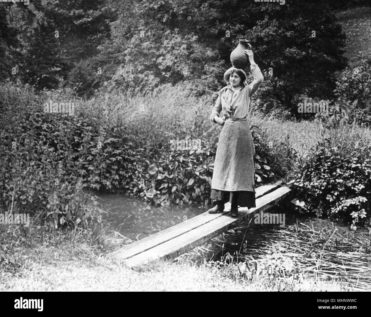 Countrywoman che porta un piatto su un ponte, 1890s Foto Stock