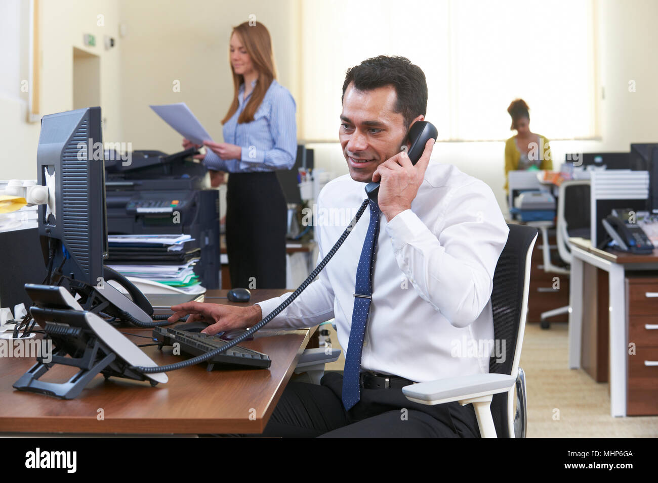 Imprenditore rendendo chiamata alla scrivania in ufficio occupato Foto Stock