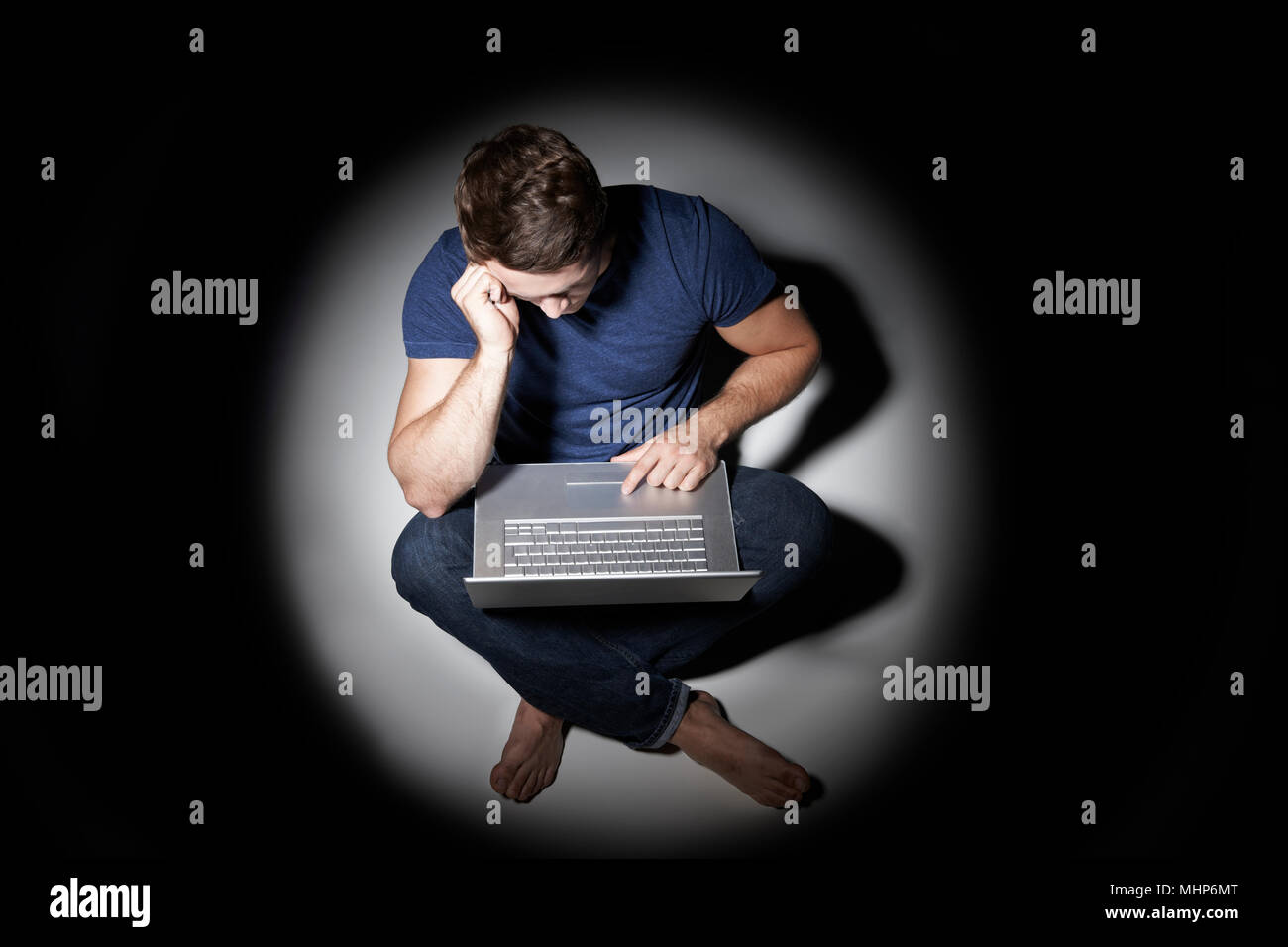 Giovane uomo utilizzando laptop in piscina di luce Foto Stock