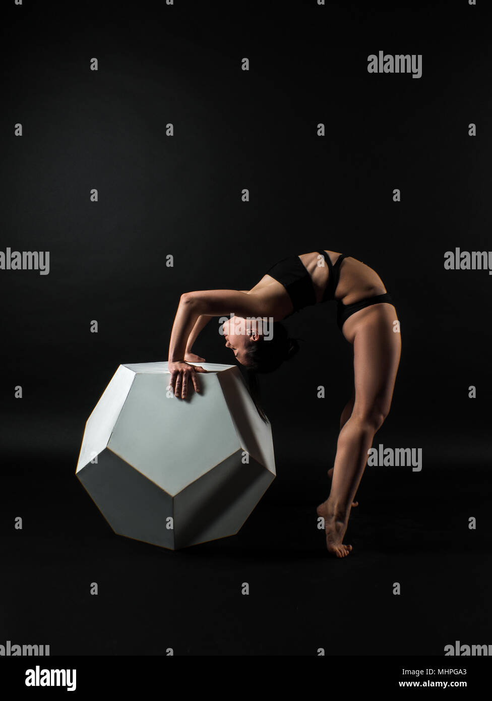 Montare sportivo darkhair donna in nero sportswear lavorando in studio con sfondo nero. Dancing, allungando, Standing pilates, yoga e fitness pone Foto Stock