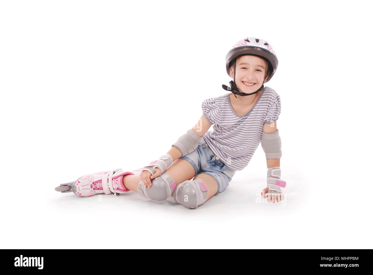 Felice bambina con pattini a rotelle e gli indumenti di protezione in appoggio - isolato su sfondo bianco Foto Stock