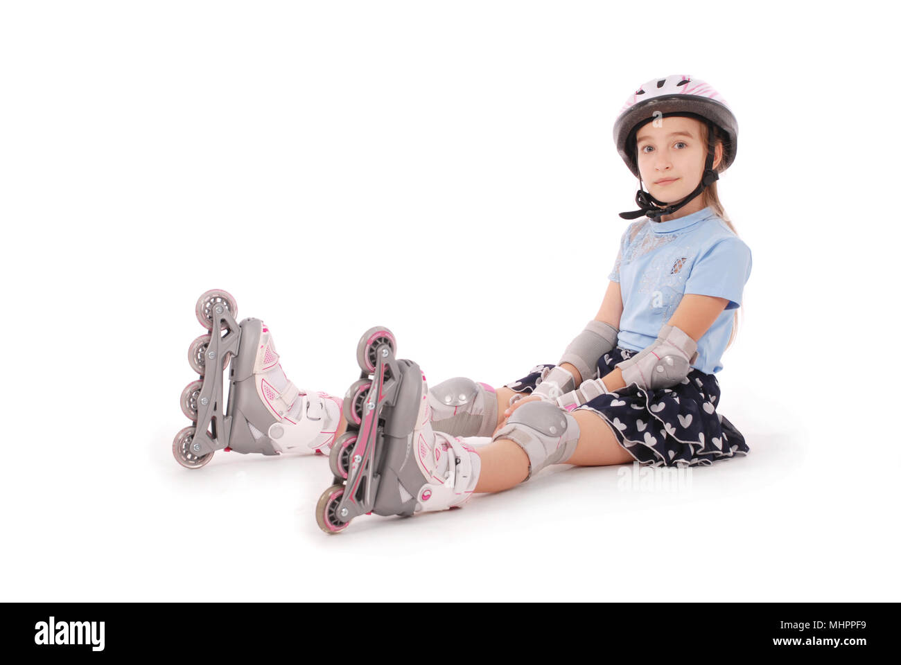 Felice bambina con pattini a rotelle e gli indumenti di protezione in appoggio - isolato su sfondo bianco Foto Stock