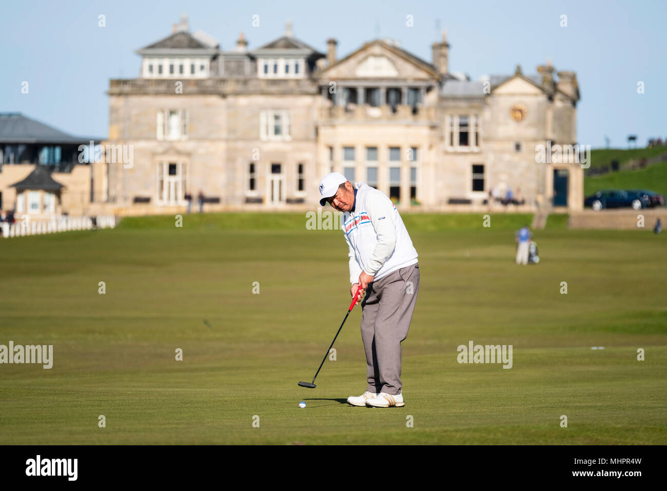 Asian golfista mettendo al diciassettesimo verde ( road hole) e club house del Royal and Ancient Golf Club (R&A) Old Course a St Andrews Fife, Scozia, Foto Stock