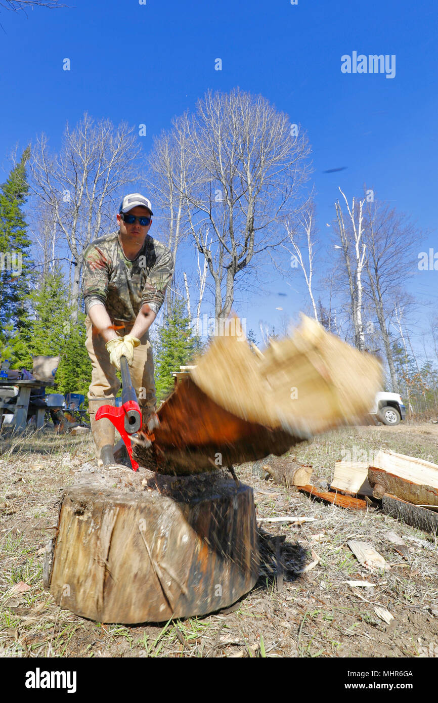 Un uomo che scinde legna da ardere con un'ascia. Foto Stock