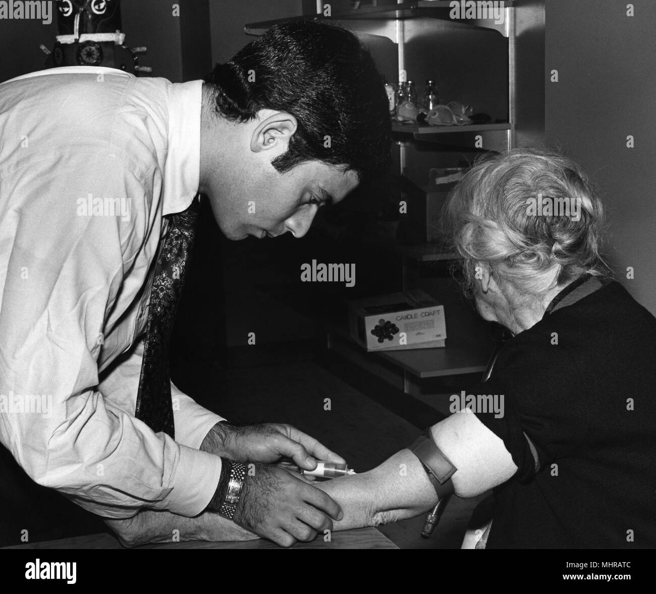 La sanità pubblica lavoratore prendendo un campione di sangue da una donna più anziana, 1976. Immagine cortesia di centri per il controllo delle malattie (CDC). () Foto Stock