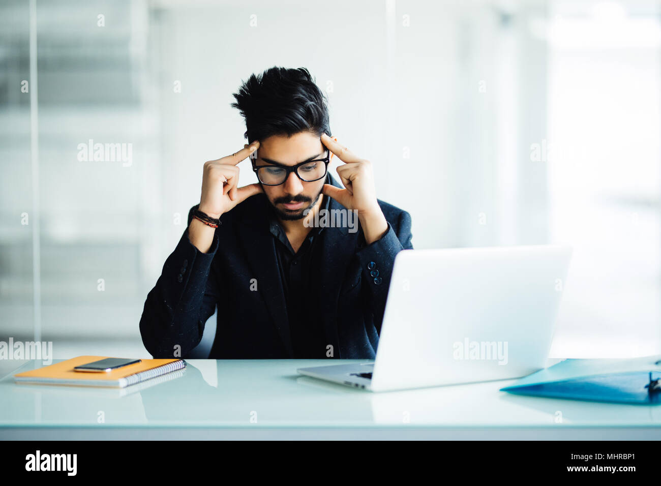 Closeup ritratto di un ragazzo impegnato nel pensiero profondo mentre guardando il suo laptop, studiare gravi, isolata su una città e natura sfondo in casa sua o Foto Stock