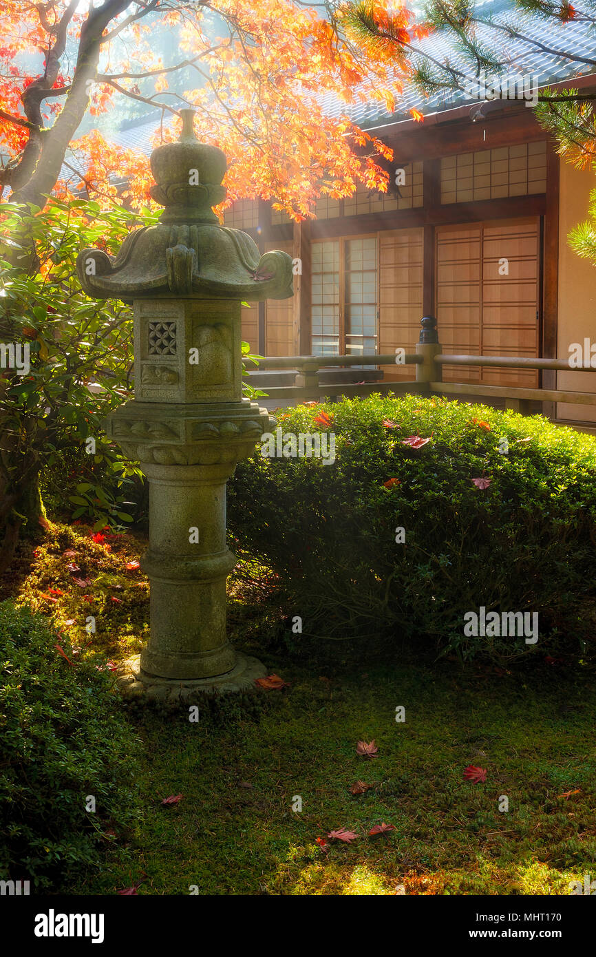 Raggi di sole su pietra pagoda lanterna dal pavilion al giardino giapponese durante la stagione autunnale Foto Stock