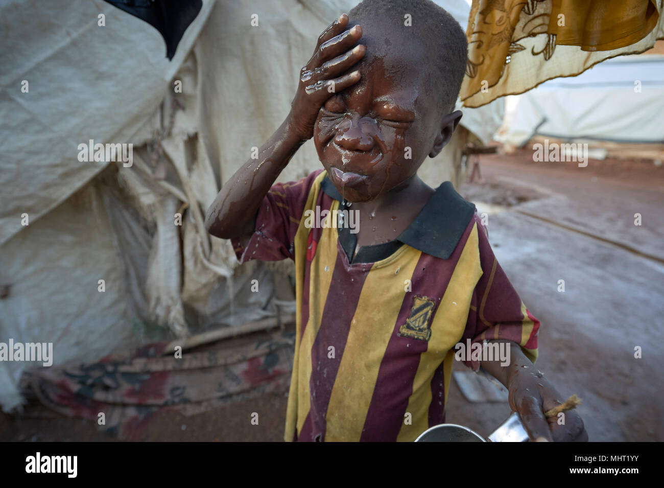 Un ragazzo lava il suo volto in un sfollati accampamento presso la Santa Famiglia chiesa cattolica di Wau, Sud Sudan. Foto Stock