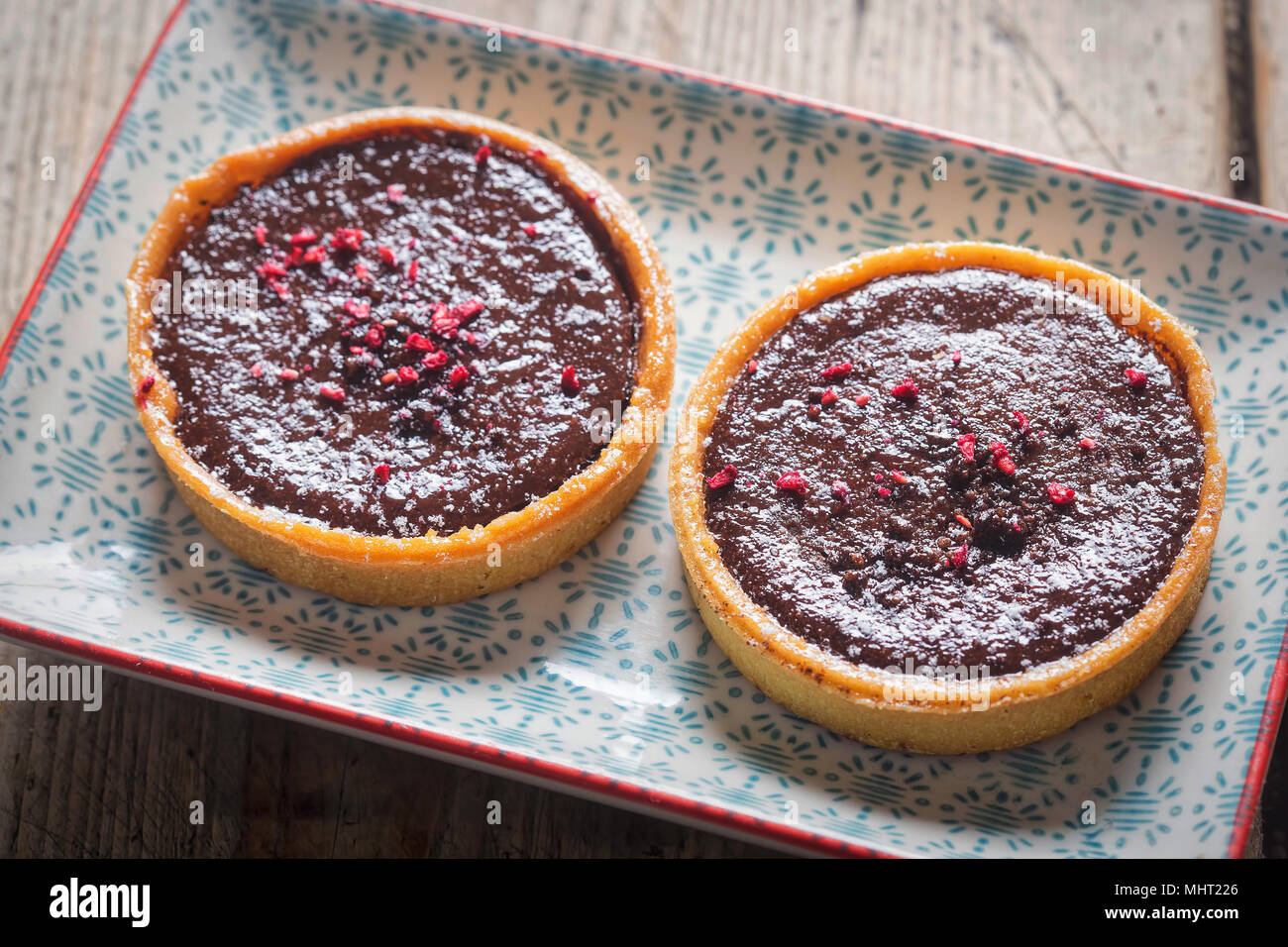 Lampone e cioccolato fondente tart. Tutto il burro crostata di pasta con ripieno di cioccolato e lamponi centro conserva, finito con lampone e cioccolato Foto Stock