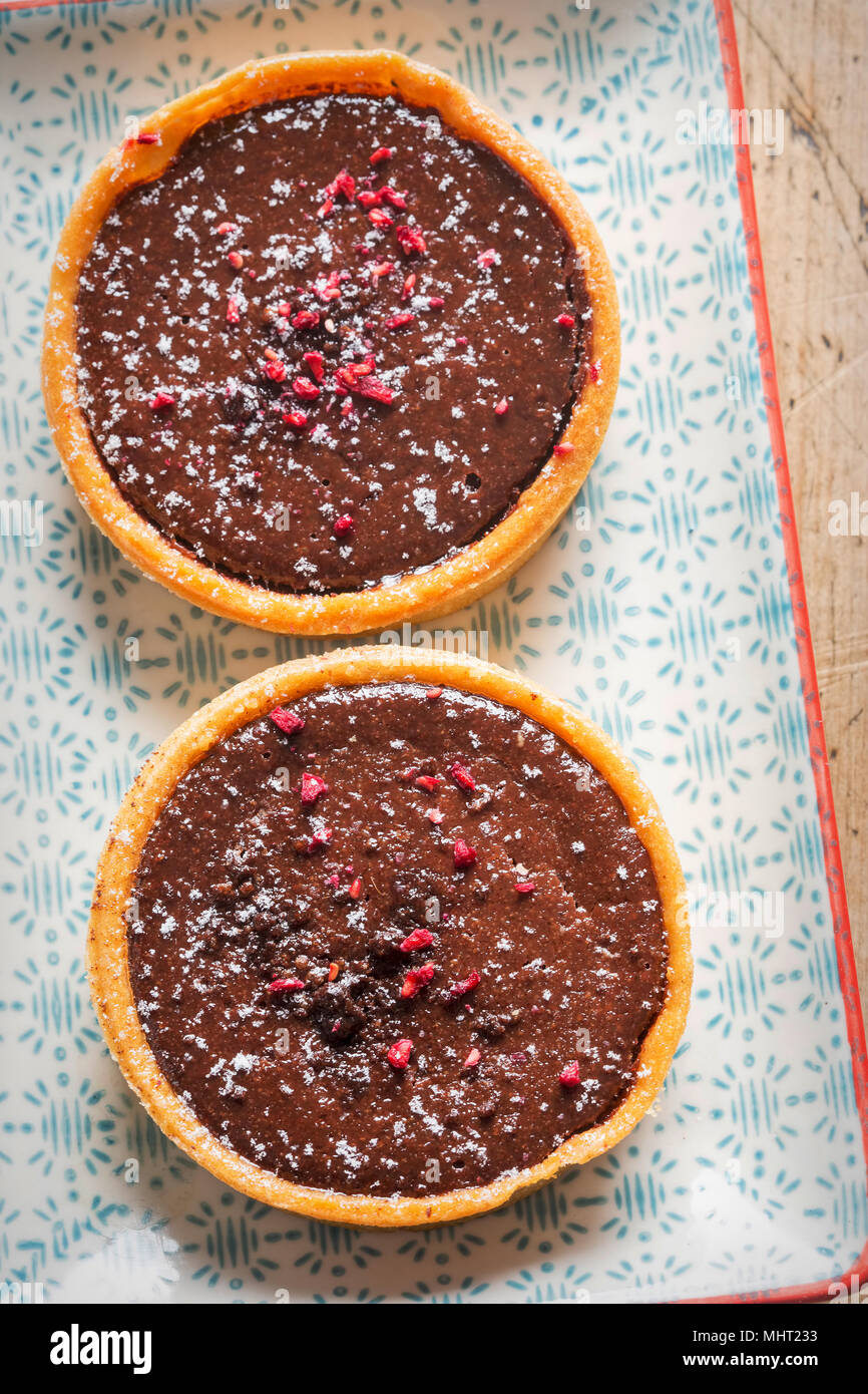 Lampone e cioccolato fondente tart. Tutto il burro crostata di pasta con ripieno di cioccolato e lamponi centro conserva, finito con lampone e cioccolato Foto Stock