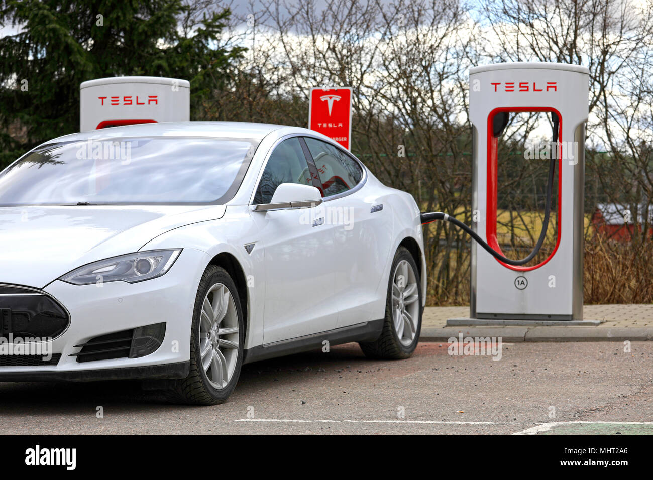 Bianco modello Tesla S auto elettrica collegata e la carica a Supercharger station su un giorno di primavera in Paimio, Finlandia - 28 aprile 2018. Foto Stock