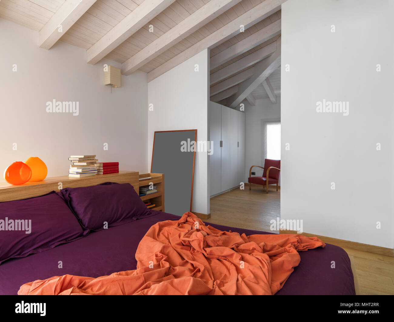 Scatti di interni di una moderna camera da letto in mansarda camera in primo piano il letto in legno il pavimento è in legno Foto Stock