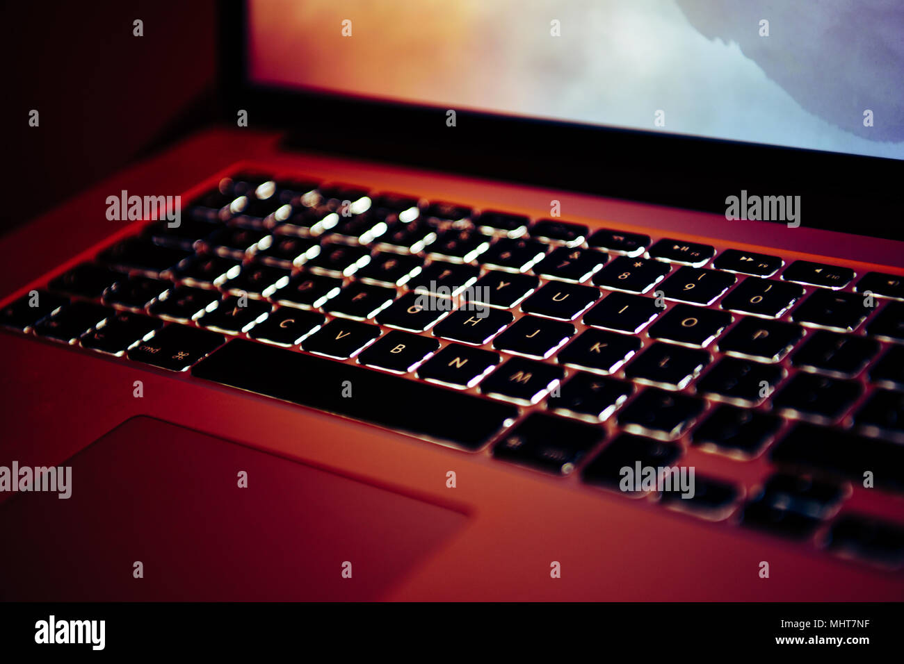 Lo schermo del notebook e la tastiera incandescente in un design studio Foto Stock