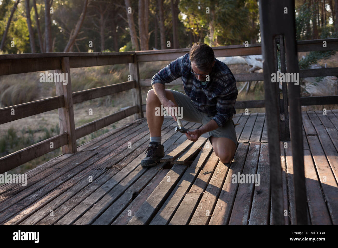 L'uomo la rimozione di pavimenti di legno duro del portico di cabina Foto Stock