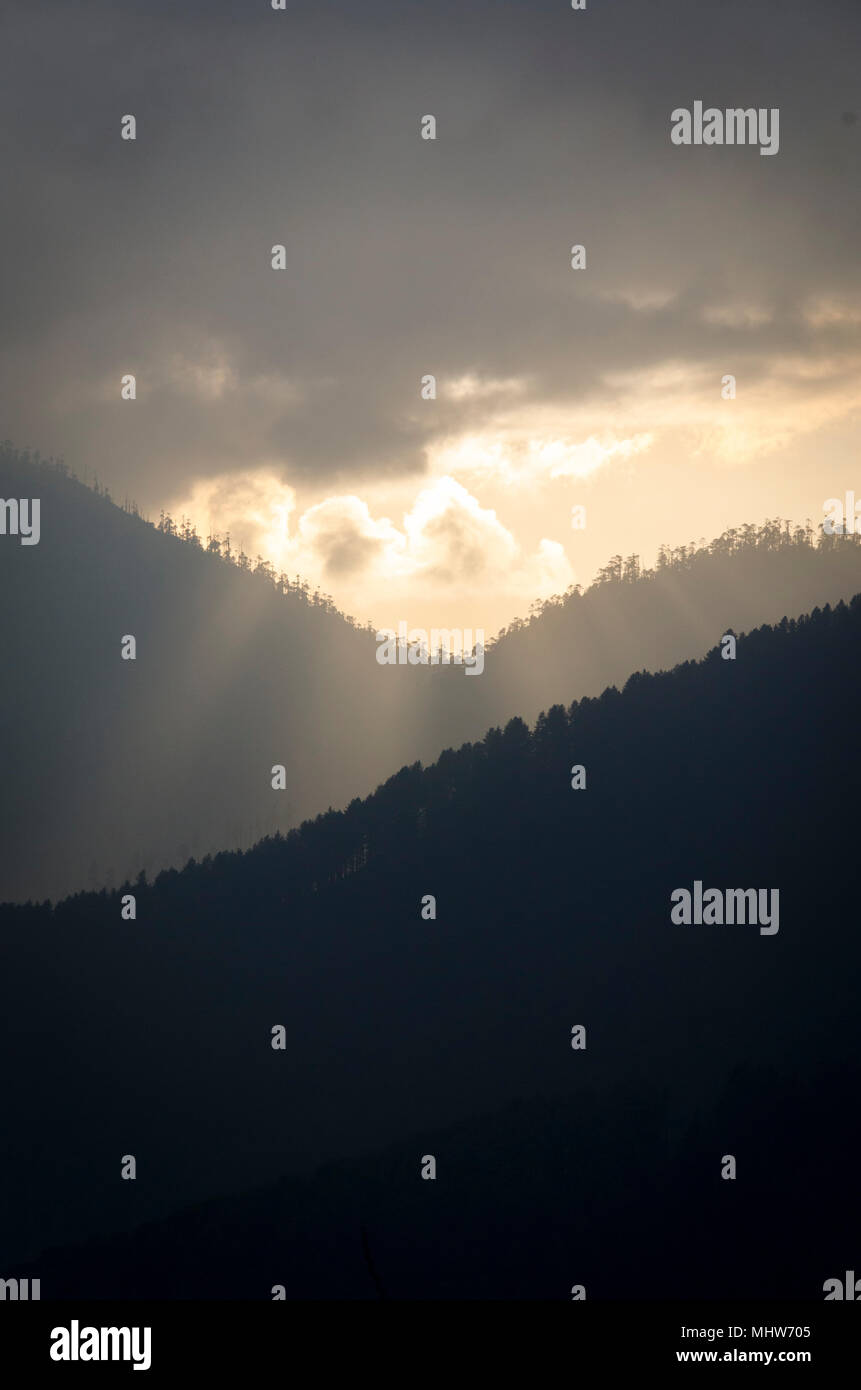 Sole che splende attraverso le nuvole, oltre le gamme della montagna, Phobjikha Valley, Wangdue Phodrang, Bhutan Foto Stock
