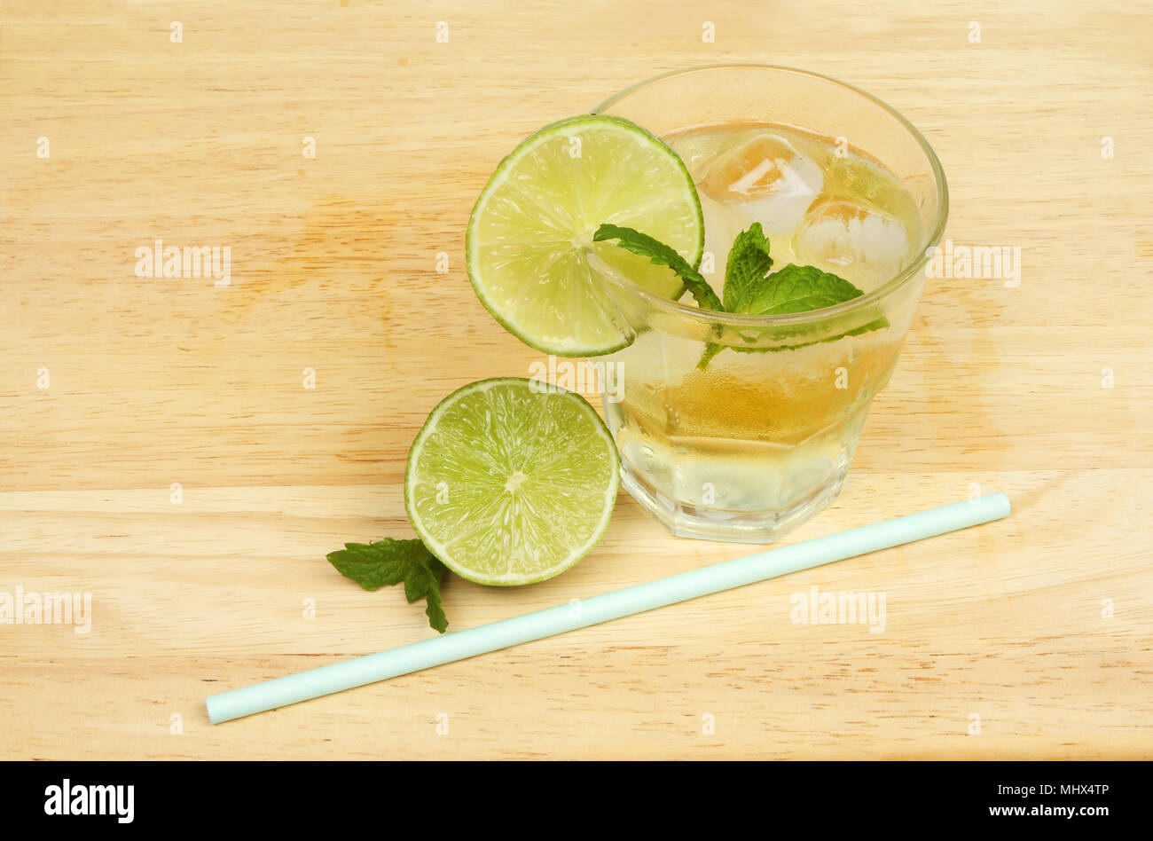 Il succo di lime cordial drink con calce e una cannuccia ona tavola di legno Foto Stock