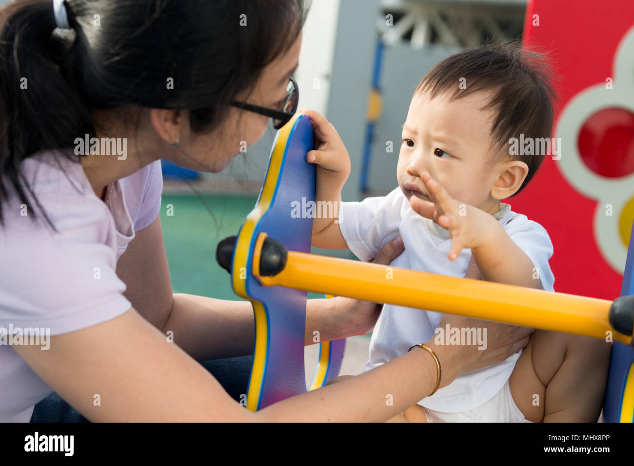 Donna asiatica con il suo bambino al parco giochi Foto Stock