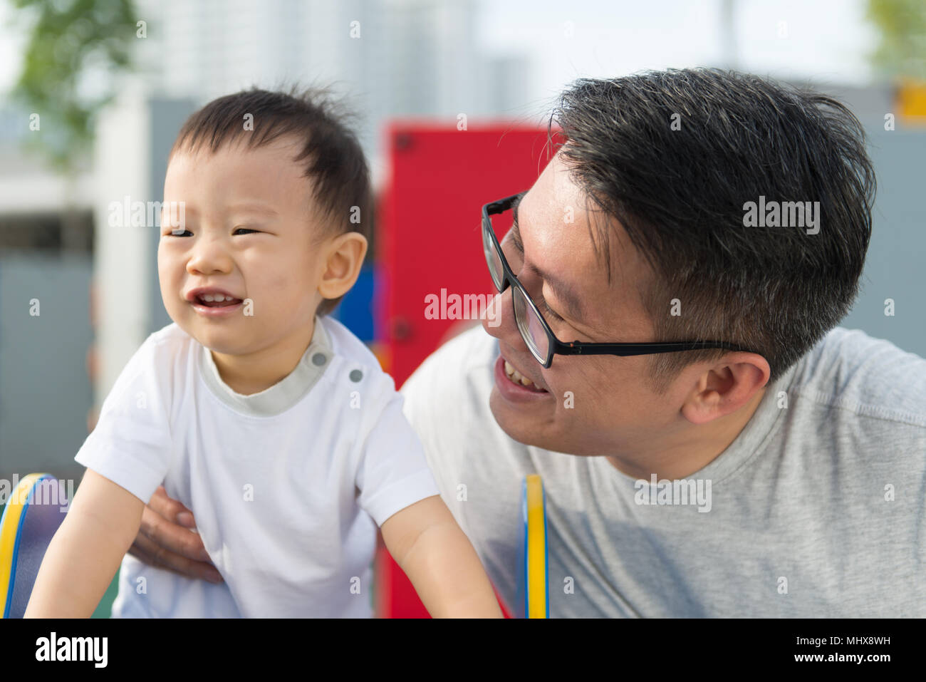 Padre asiatico con il suo piccolo ragazzo al parco giochi Foto Stock