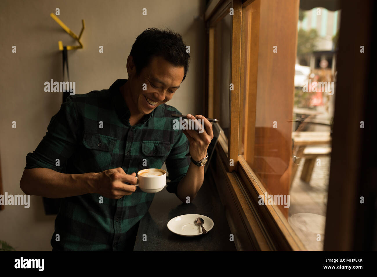 Imprenditore parlando al telefono cellulare mentre un caffè presso la caffetteria Foto Stock