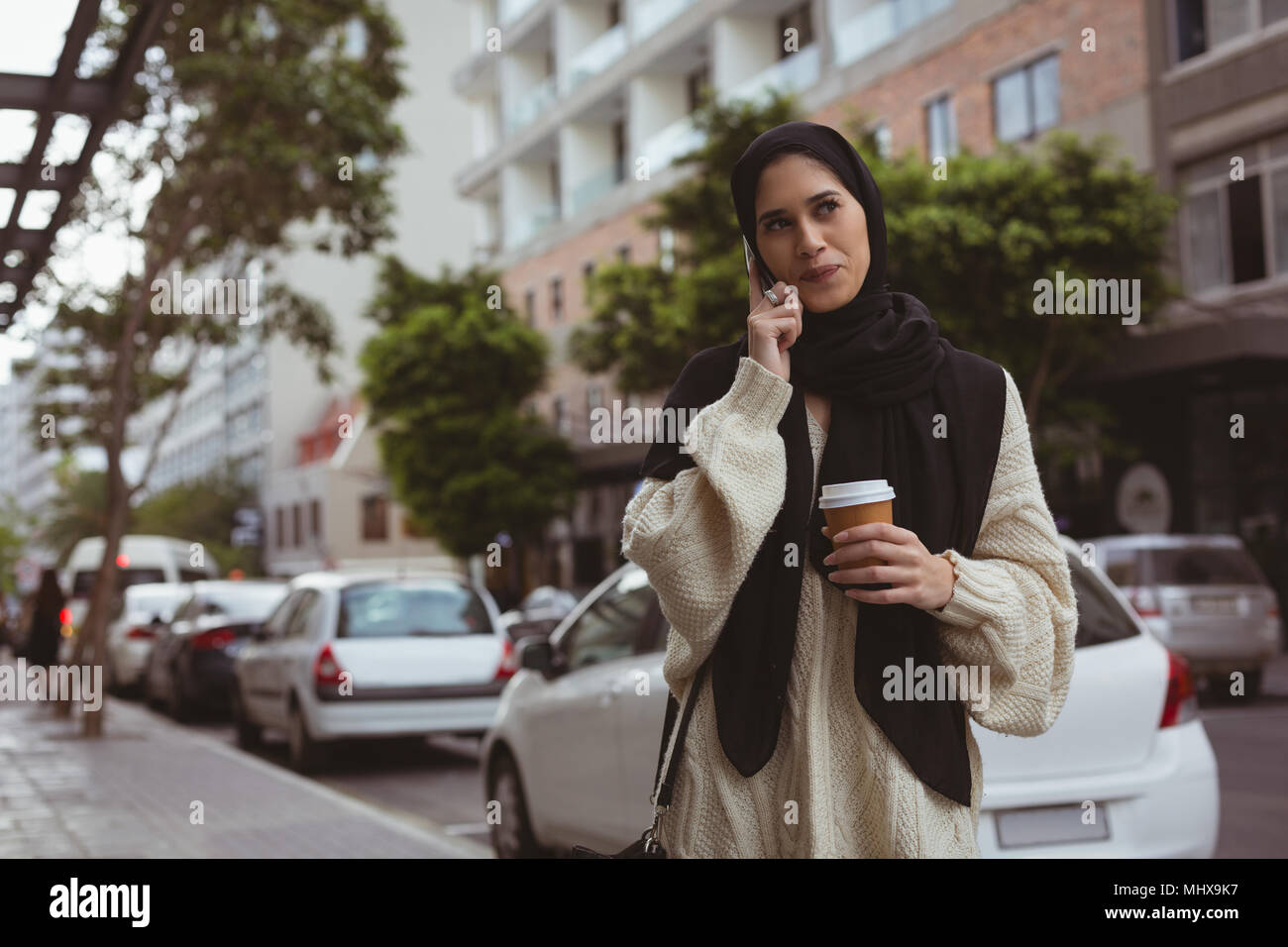 Il hijab donna parlando al telefono cellulare mentre un caffè Foto Stock