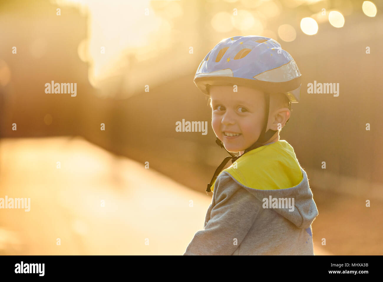 Sorridente aussie ragazzo che indossa il casco e in sella alla sua bicicletta un giorno a Glenelg, Sud Australia Foto Stock