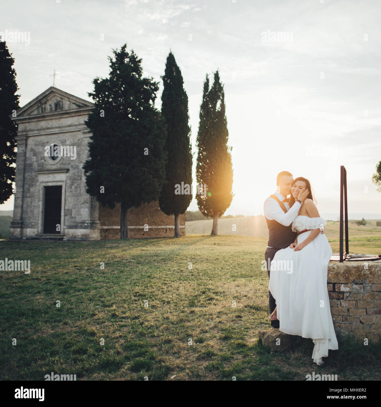 Felice sorridente alla moda giovane a piedi e baciare in Toscana, Italia il loro giorno delle nozze. Foto Stock