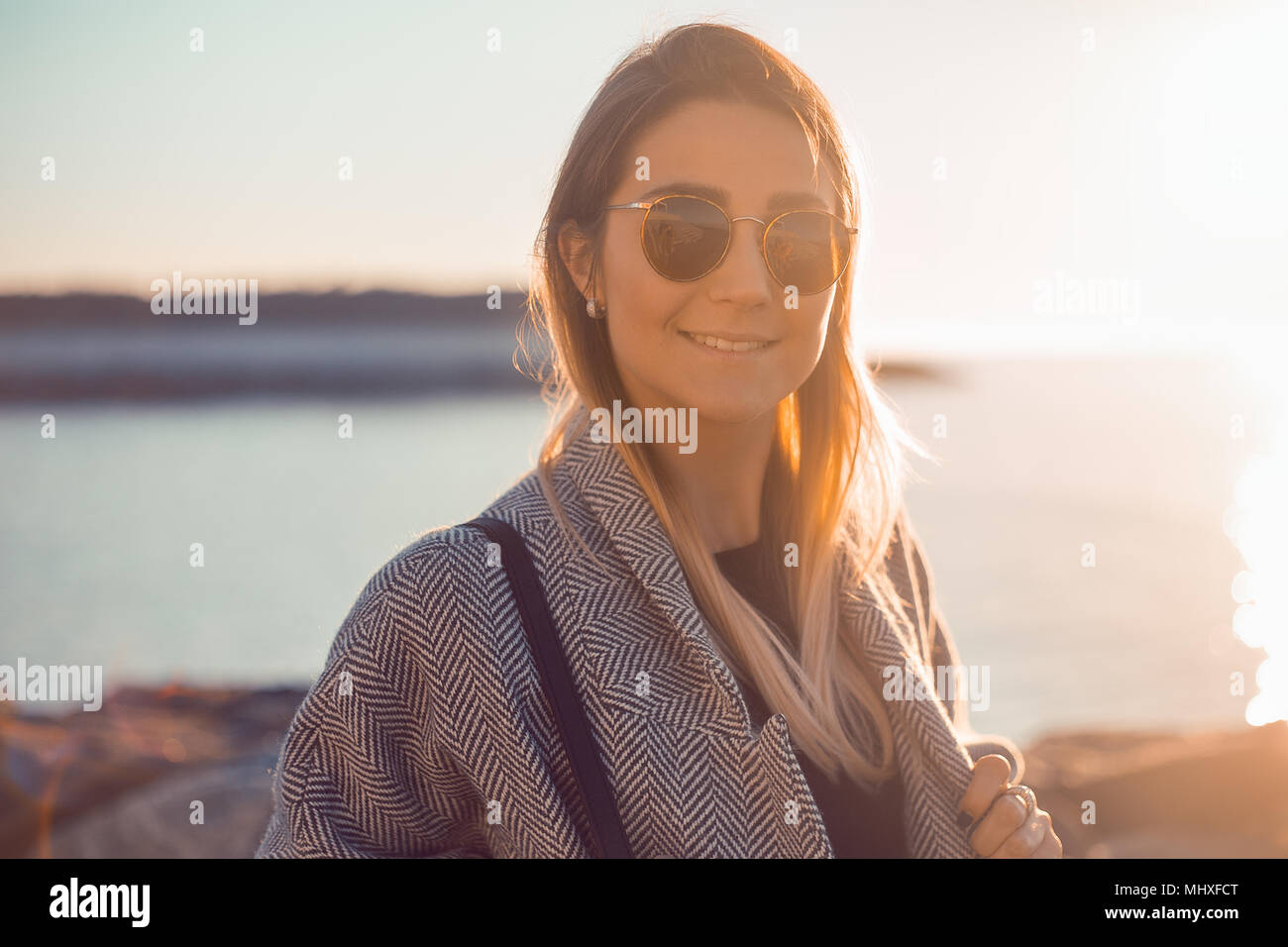 Ritratto di donna che indossa gli occhiali da sole guardando sorridente della fotocamera Foto Stock