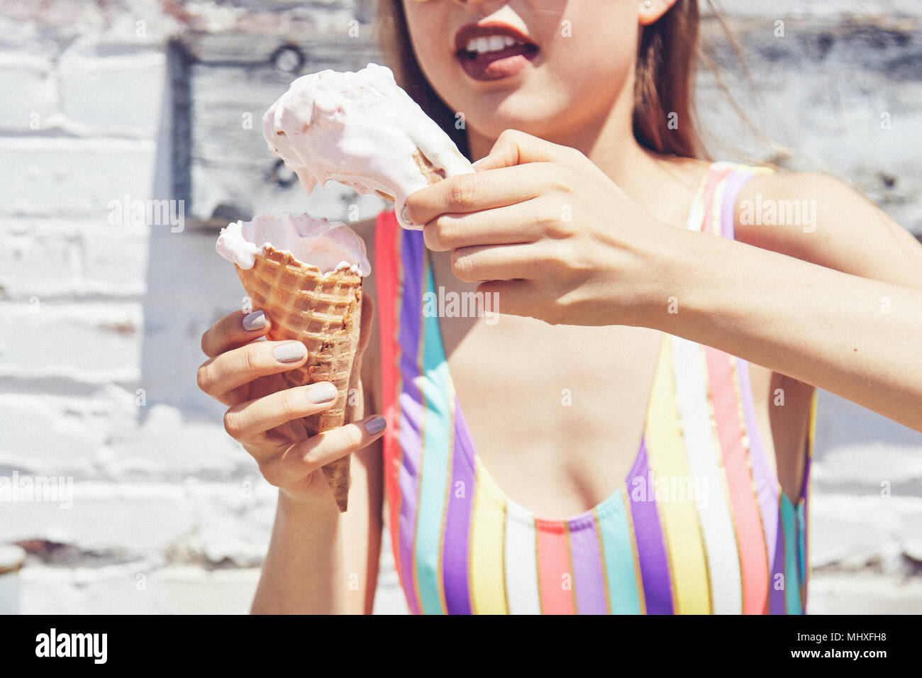 Giovane donna tenendo la fusione di due coni gelato, ritagliato Foto Stock