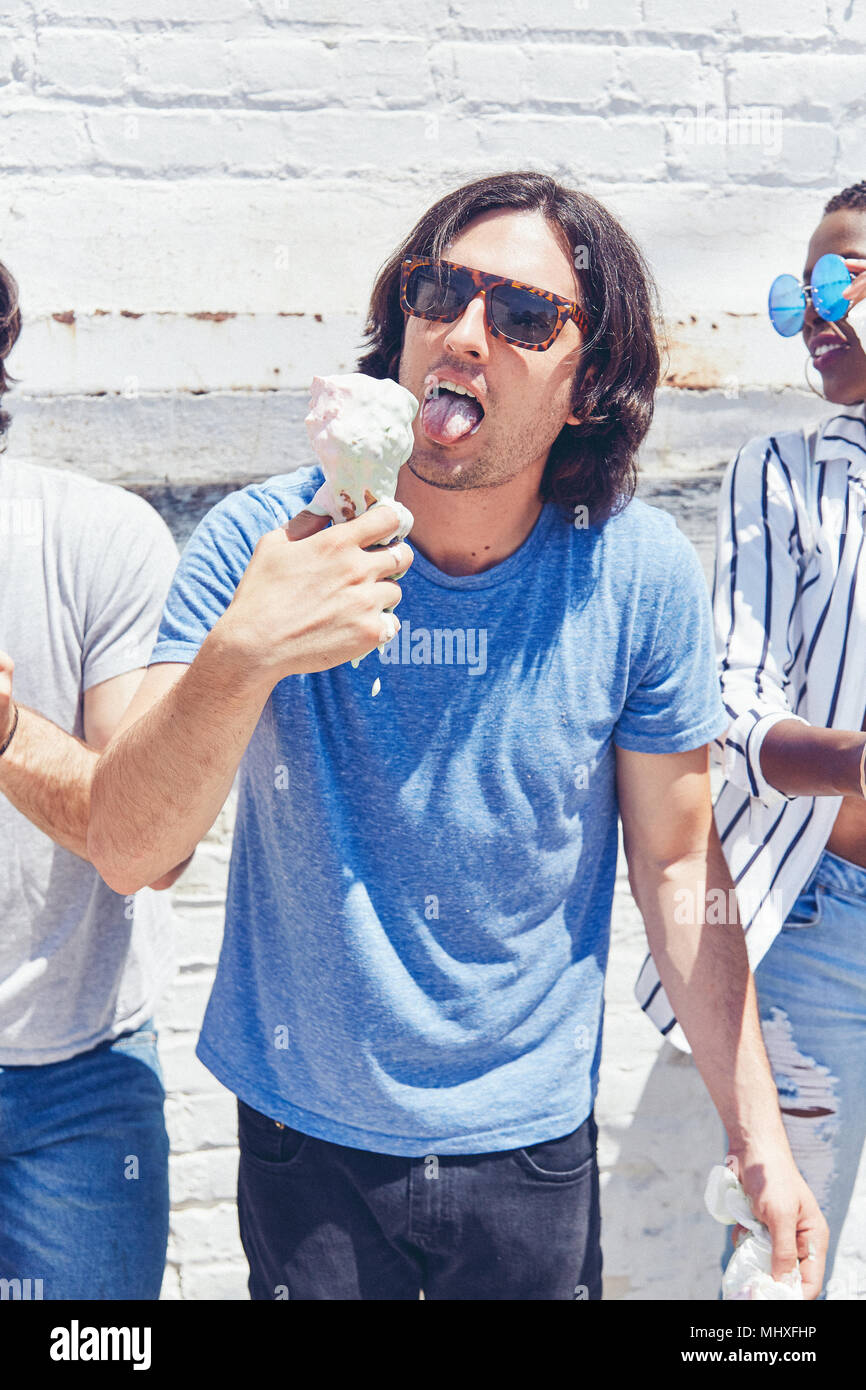 Giovane uomo leccare la fusione cono gelato, ritagliato Foto Stock