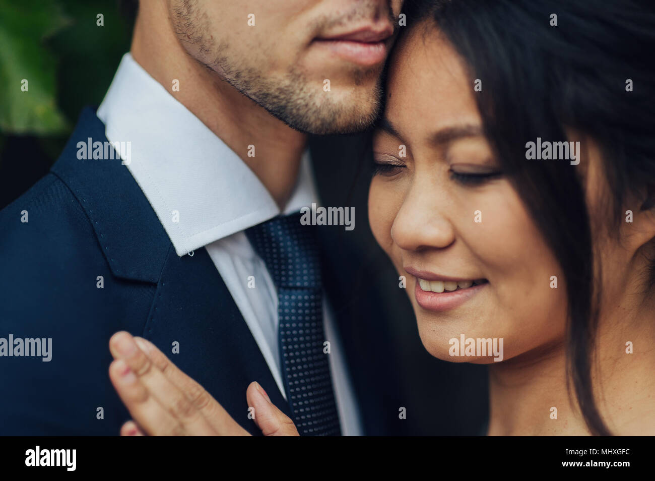 Ritratto di elegante bride asiatico abbracciando lo sposo Foto Stock