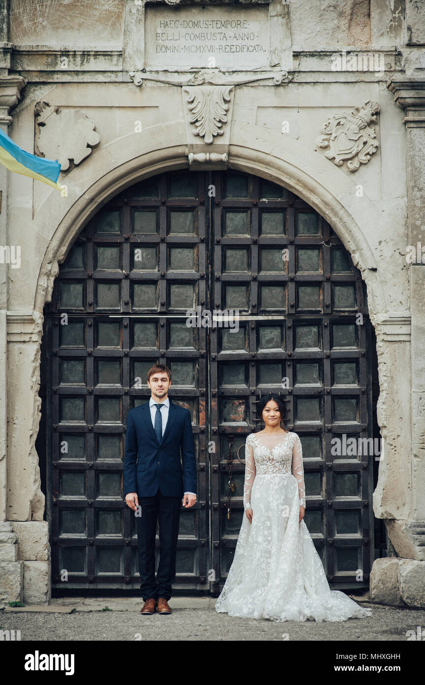 Bride asiatico con lo sposo in posa nella parte anteriore della porta di antiquariato Foto Stock