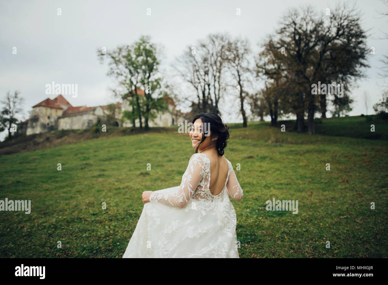 Bride asiatico in elegante abito da sposa in esecuzione per esterno Foto Stock