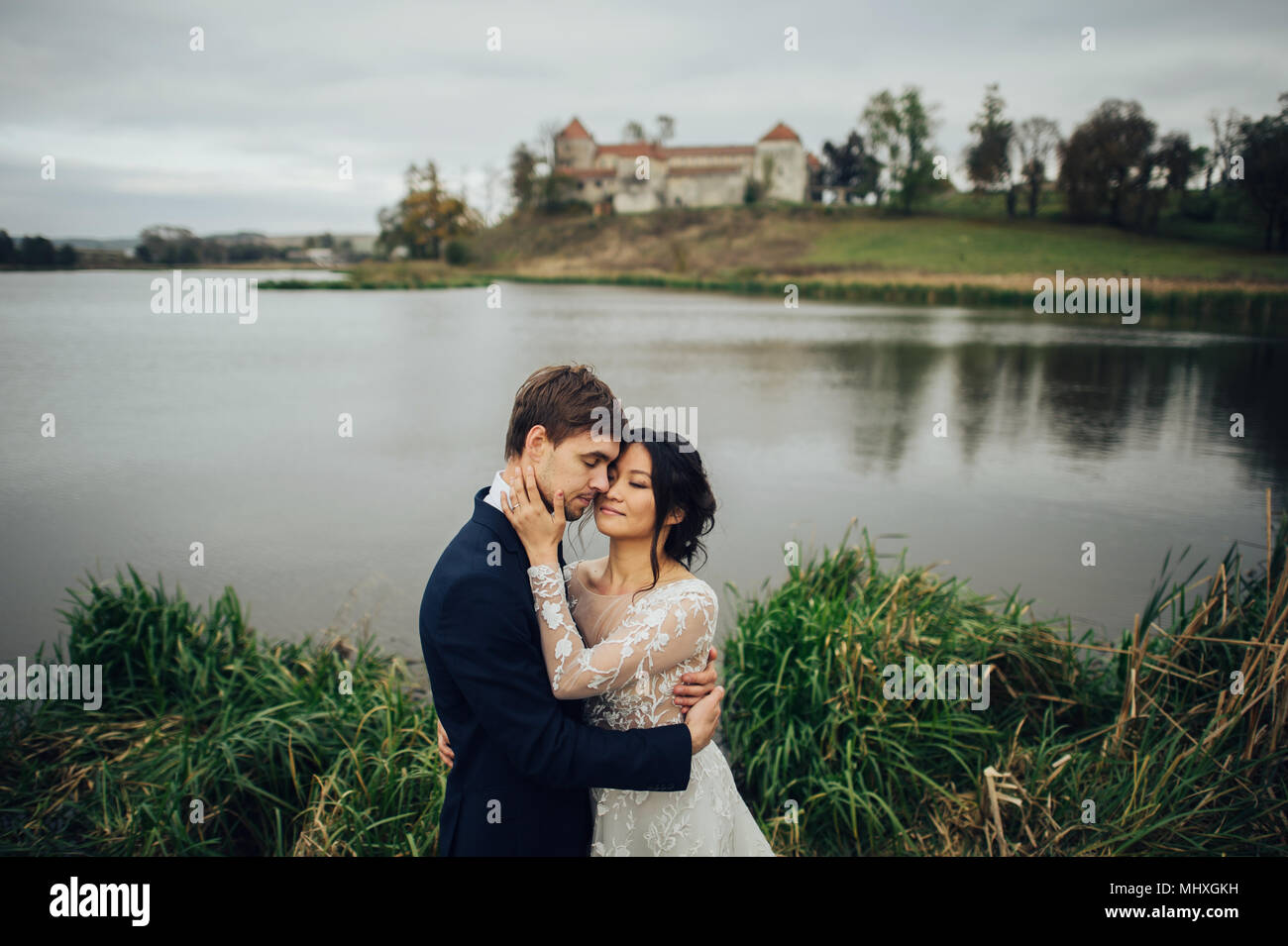 Felice coppia di sposi bacio al tramonto con il muro di castello sullo sfondo Foto Stock