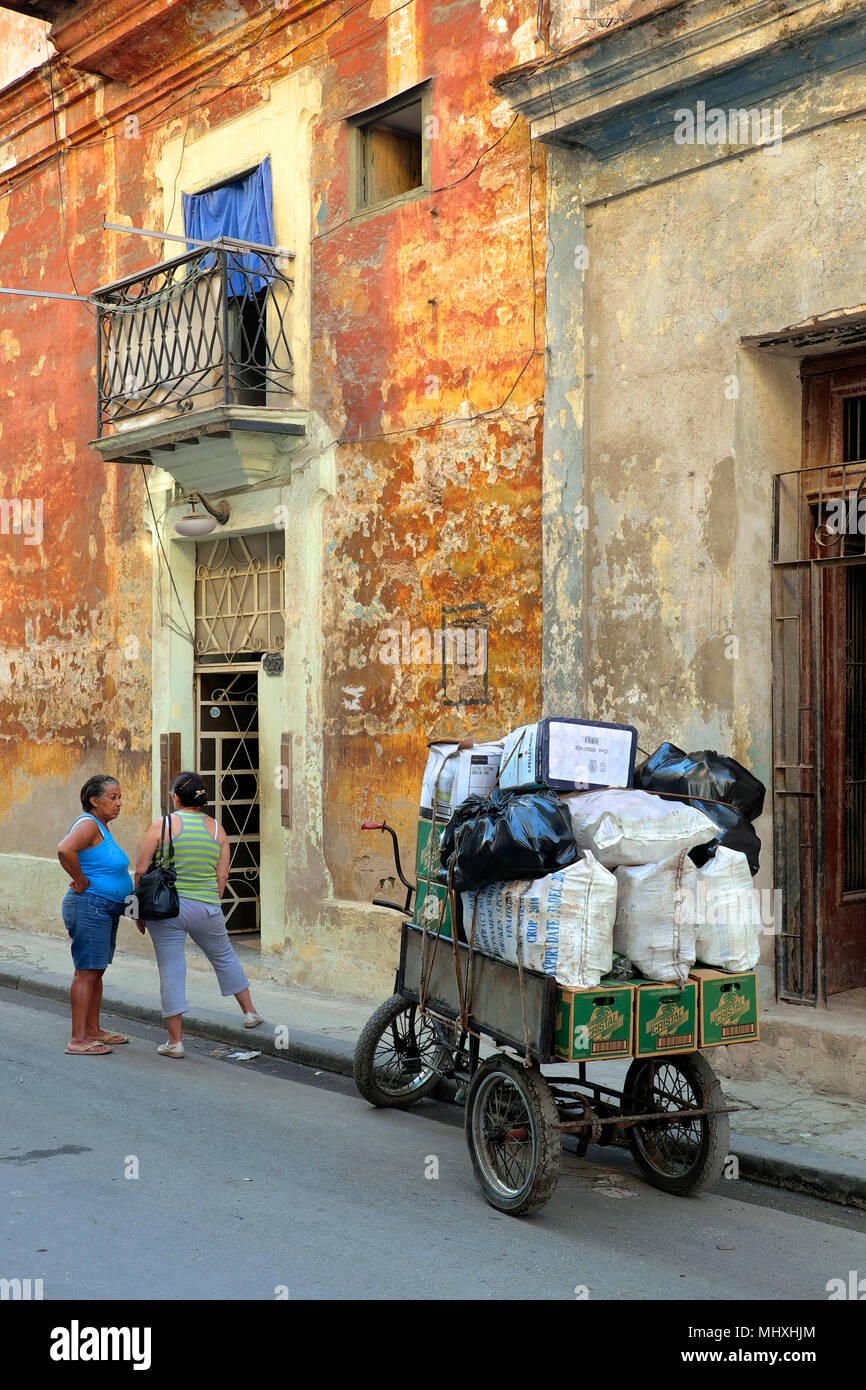 Conversazione tra due donne accanto a una di tre ruote bicicletta con sacchi di riciclaggio di lattine e altri rifiuti, Havana, Cuba Foto Stock