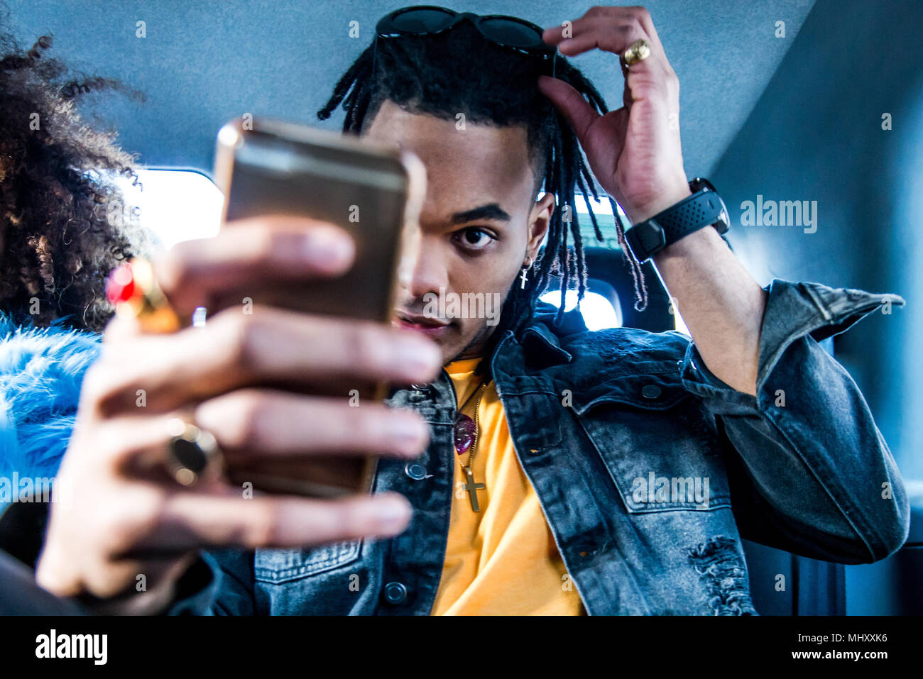 Giovane uomo nel retro del taxi, utilizza lo smartphone, capelli di fissaggio Foto Stock