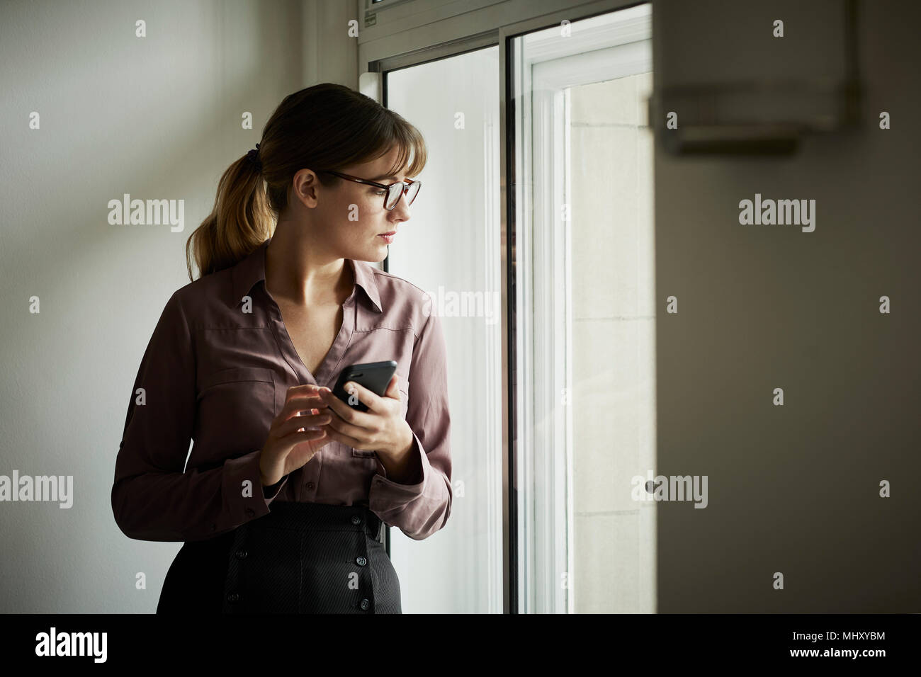 Imprenditrice guardando fuori della finestra pensively Foto Stock