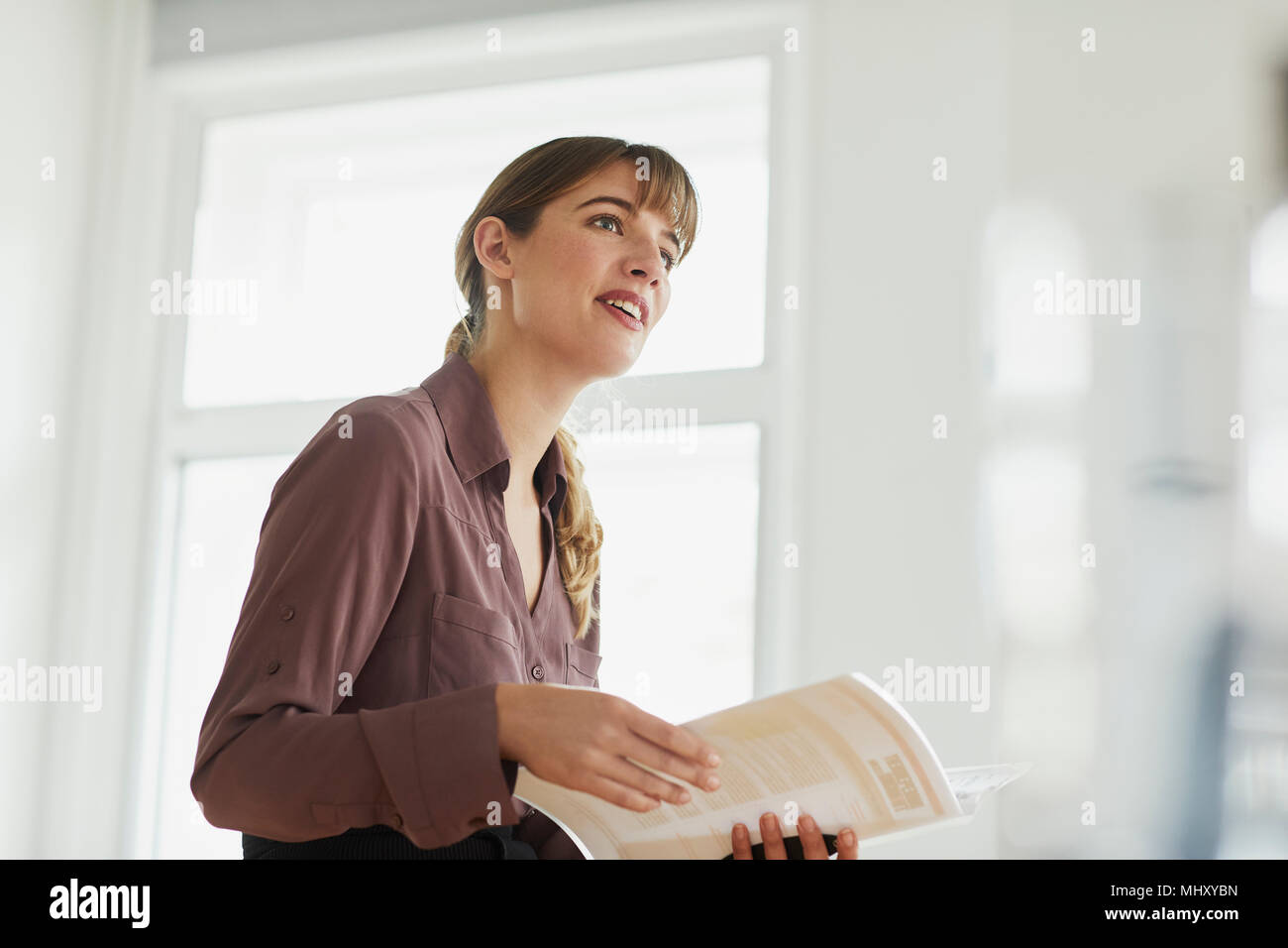 Imprenditrice ufficio in azienda di documenti cartacei che guarda lontano Foto Stock