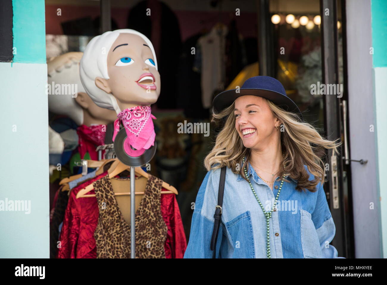 Giovane donna lasciando negozio di abbigliamento sorridente Foto Stock