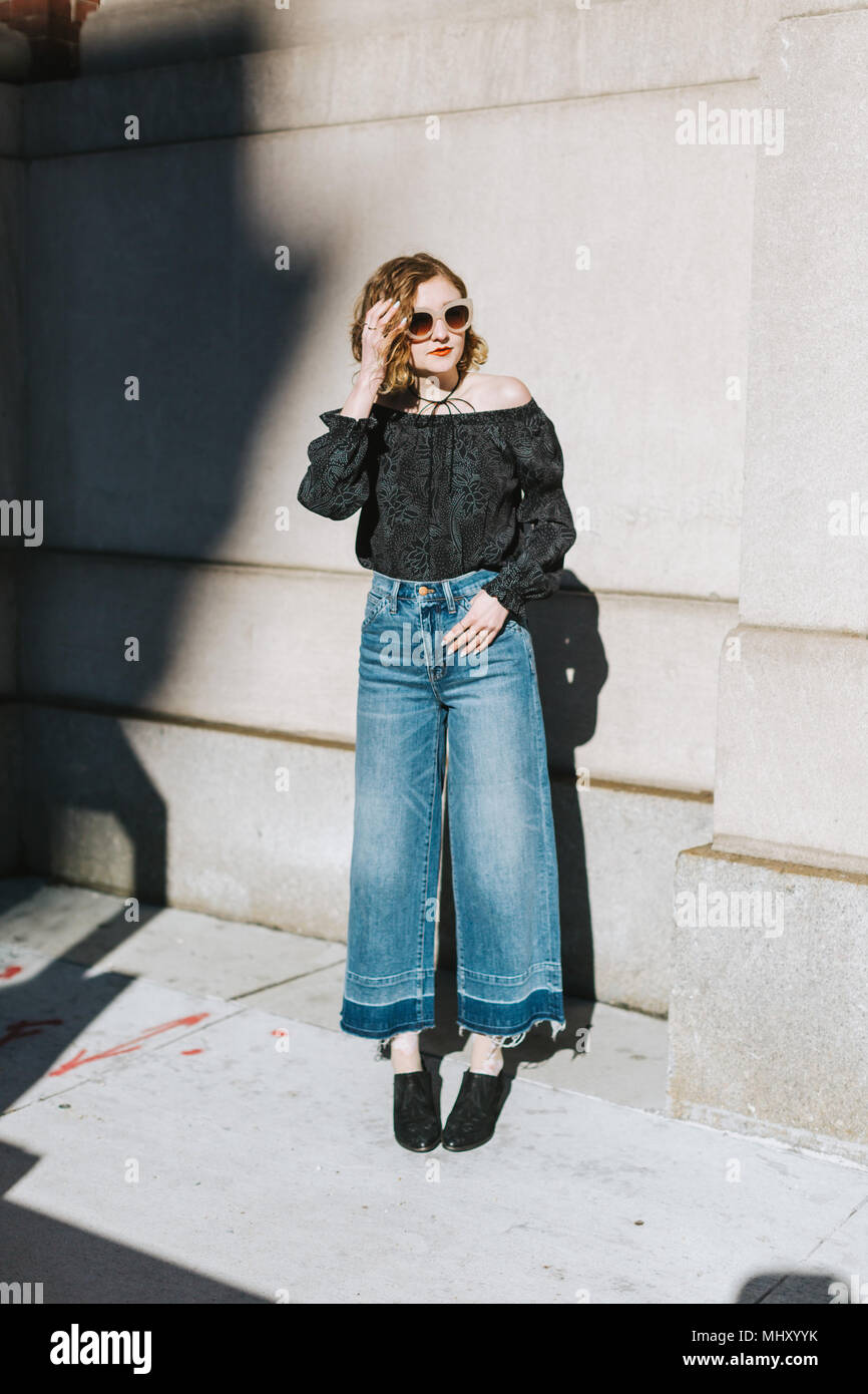 Ritratto di donna che indossa jeans svasata che guarda lontano a piena lunghezza Foto Stock